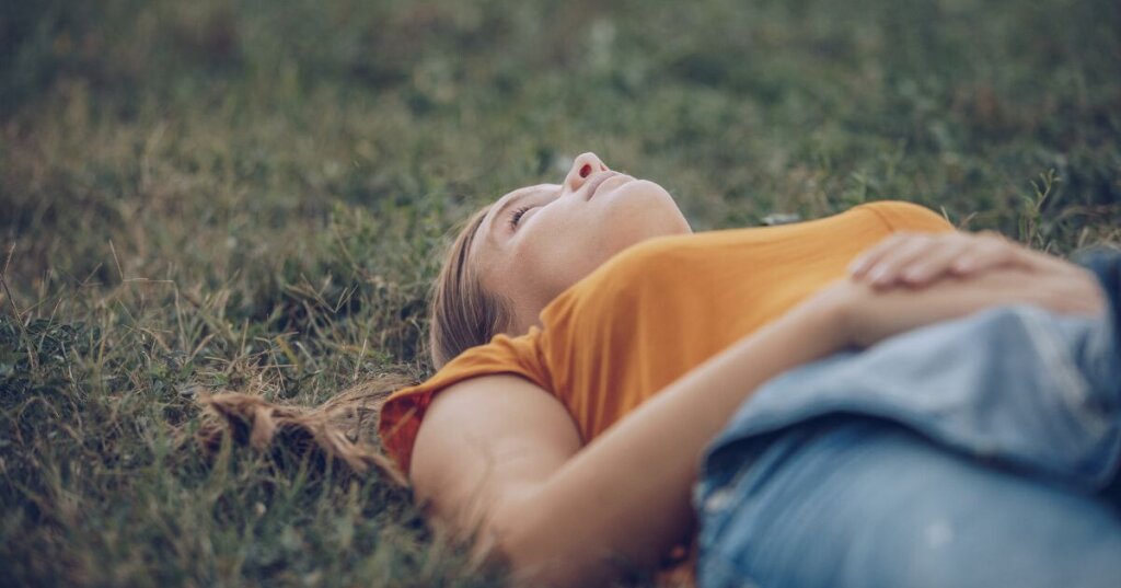 femme allongée sur l'herbe fermant les yeux